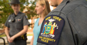 SUNY Police badge on an officer's sleeve with a student standing behind him