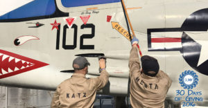 Maritime College cadets clean the side of a fighter plane.