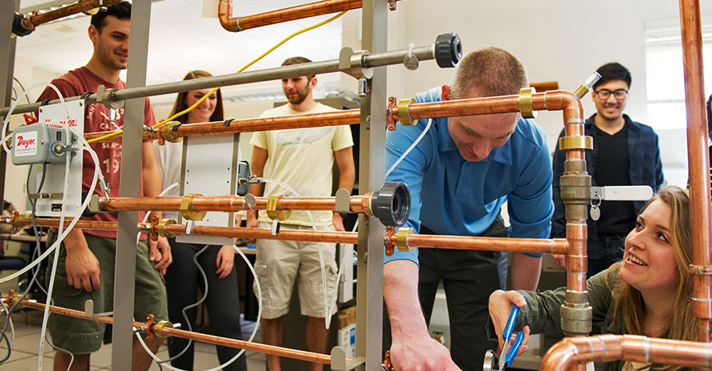 Enginnering students at SUNY New Paltz work around pipes.