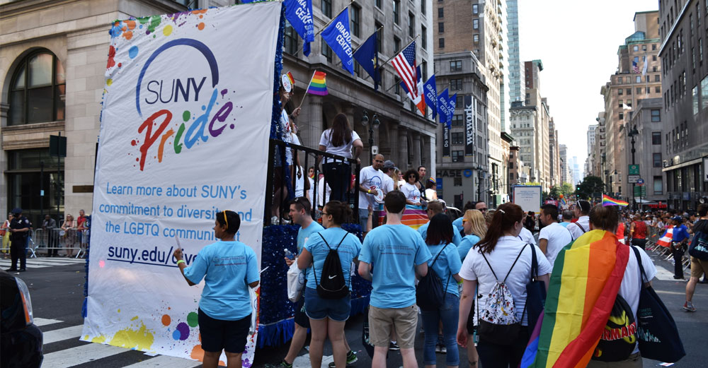 SUNY Pride float surrounded by students and parade watchers at the 2016 NYC Pride Parade