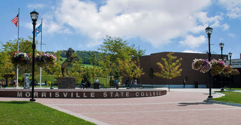 Morrisville State College letters on brick facade surrounding iron horse sculpture in middle of campus quad.