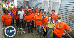 Large group of Buffalo State students pose for picture after cleaning up around a house in town.