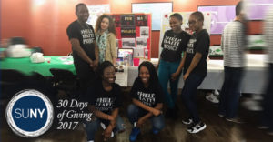 Students from WUNY Old Westbury pose in front of donations table wearing black tshirts with Help Haiti Project.