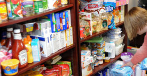 Female reaching down for items in a food pantry.