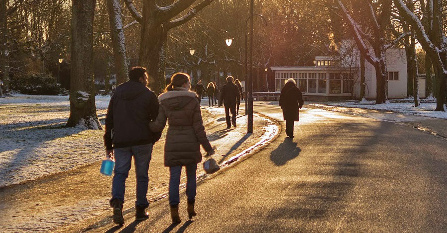 People walking a curved street in a park in winter.