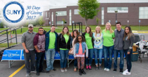SUNY Poly students outdoors in front of a table with Make A Wish table drape.