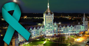 SUNY Plaza at night in teal lights with teal ribbon over top for sexual assault awareness