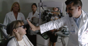 A male doctor works with an old, female patient as she tests a bionic eye that will allow her to process light and dark.