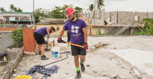 SUNY College at Brockport student shovels debris off a roof in Puerto Rico.