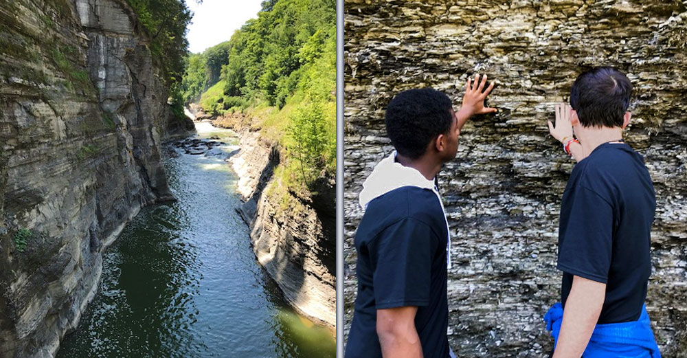 2 male EOP students from Monroee Community College touch rock wall formation at Letchworth State Park.