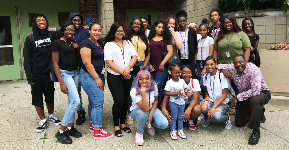 UAlbany EOP students pose outside building entrance with A Village Inc staff.