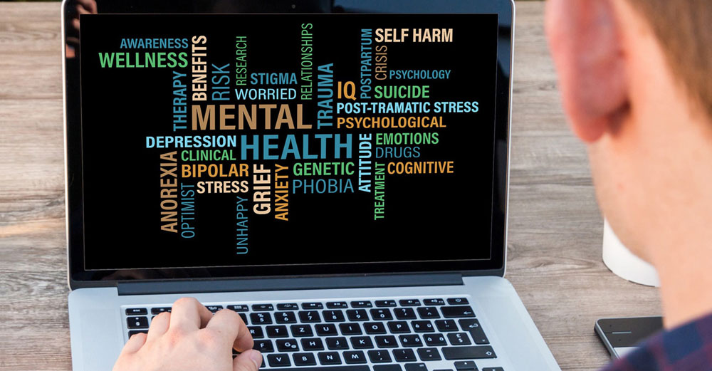 Laptop with mental health phrases on screen.