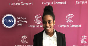 Buffalo State student Ada Boston in front of Campus Compact banner.