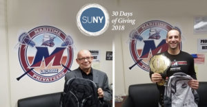 2 SUNY Maritime athletic staff hold backpacks for donation.