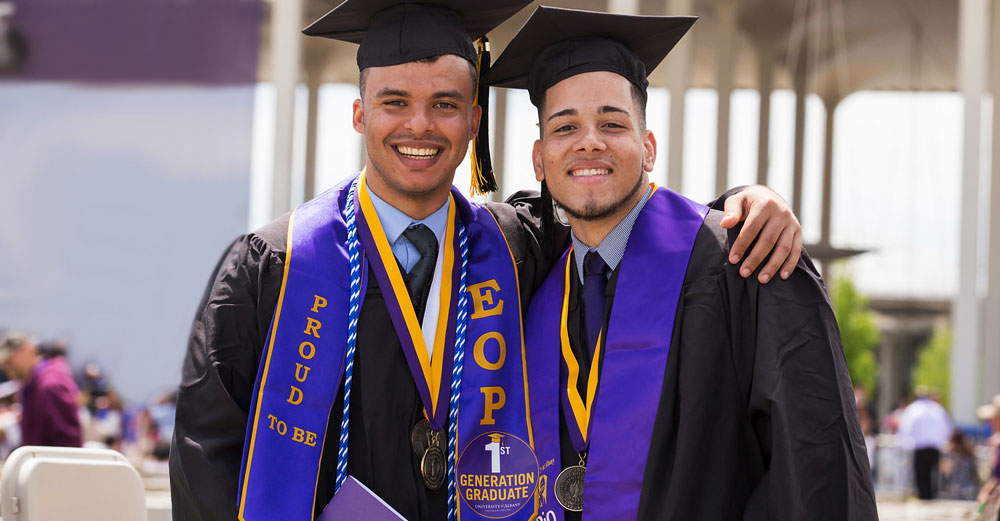 AN EOP graduate poses with arm around friend at commencement.