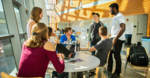 Students sit and talk at tables of a University at Buffalo student lounge.