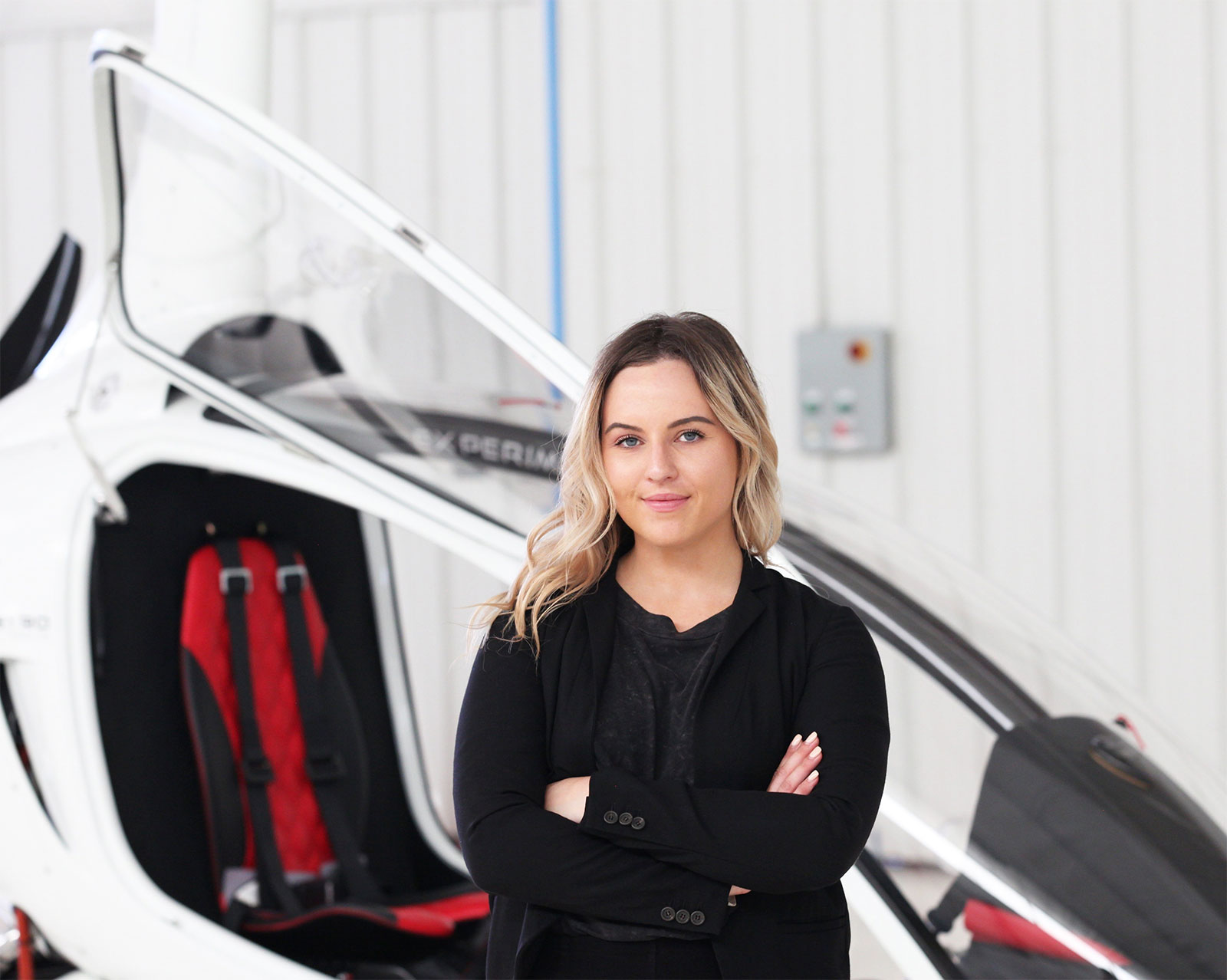 Kristen Steinhardt, Farmingdale State College graduate, stands in front of a gyroplane with cabin window open. 