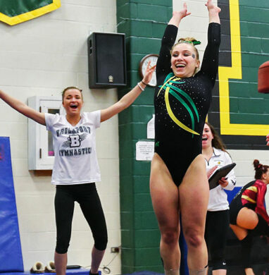 A member of the College at Brockport womens gymnastics team smiles at the end of her vault routine.