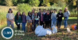 SUNY ESF students pose outside under a tree after raking leaves.