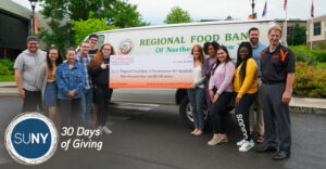 SUNY Cobleskill students and staff stand with a giant check in front of Regional Food Bank van.