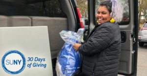 SUNY Purchase College student loads clothing donations into van.