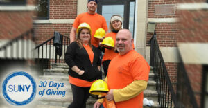 Jamestown Community College students and staff in vests and hard hats outide a brick building.