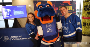 SUNY's Got Your Back posing with Islanders mascot at event while holding comfort bags for sexual and domestic violence victims/survivors