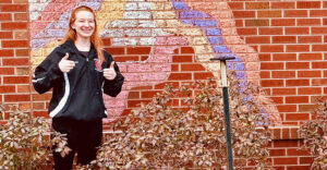 Student Hunter Crawley smiles in front of brick wall.