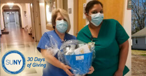 2 healthcare workers stand in hospital hallway with gft basket in hand