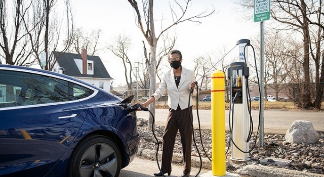 Person plugs in a blue car at an electric car charging station