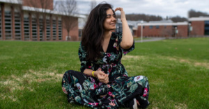Fabiha Khan sits in the grass on campus at MOhawk Valley Community College.