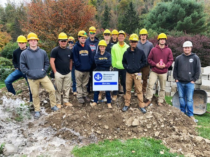 Alfred State College students pose for group picture on top of pile of rubble at a construction site. 