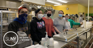 Buffalo State College students work in kitchen preparing meals for the hungry.