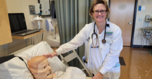female nursing student works with a mannequin patient in hospital setting.