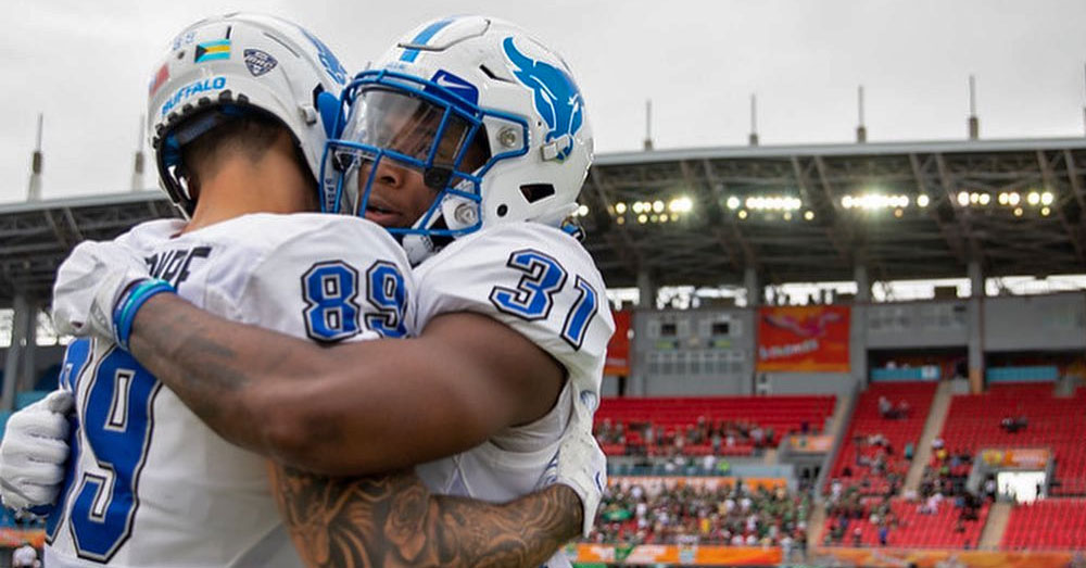 University at Buffalo football players hug on the sideline.