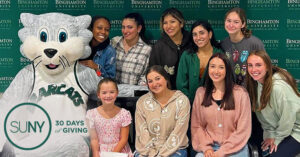 Binghamton students pose with school mascot Baxter and local children from the Children's Miracle Network Hospital.