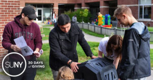 SUNY Cortland students install a compost tumbler in the Child Care Center playground area on campus.