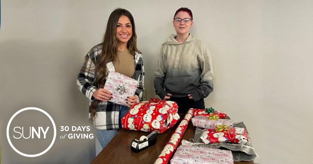 Two female Herkimer County Community College students wrapping gifts in holiday paper.