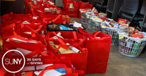 Red bags packed with food stuff laid out on the floor of a food pantry.