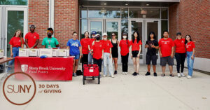 Stony Brook University students at a food drive table outside campus building.