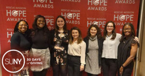 Students from Upstate Medical University pose for a picture in front of banner for Rescue Mission Hope Awards.
