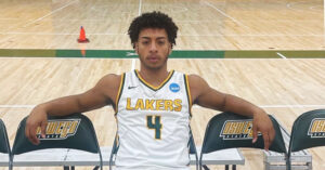 Camden Chance sits on a chair on the SUNY Oswego basketball court.