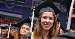 A female in her cap and gown at a Mohawk Valley Community College commencement event.
