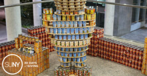 A construction of thousands of cans of food into the form of cartoon character Bob the Builder with Farmingdale State College logo on the side.