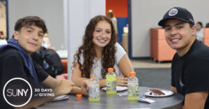 Three students at Orange County Community College seated at a table in the student lounge.