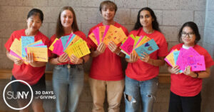 Stony Brook university students hold up cards they made to send to hospital patients.
