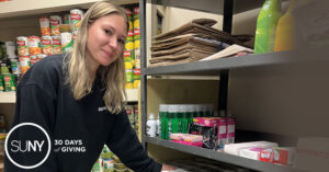 Female college student arranges food stuff on a shelf in a food pantry.