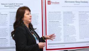 Theresa Adams presents in front of two large posters
