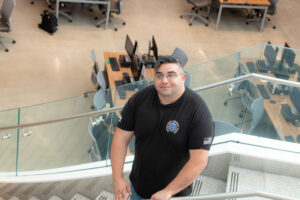 Joseph Gonzalez stands on staircase. Rows of computers sit below him.