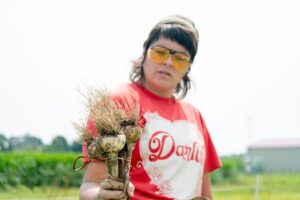 Kate Bolen clutces a clump of garlic covered in dirt.